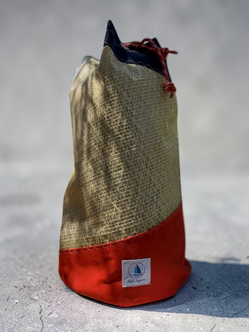 Sail Again marka, geri dönüştürülmüş yelken kumaşından üretilmiş, kırmızı ve bej renkli, büzgülü denizci sırt çantası.